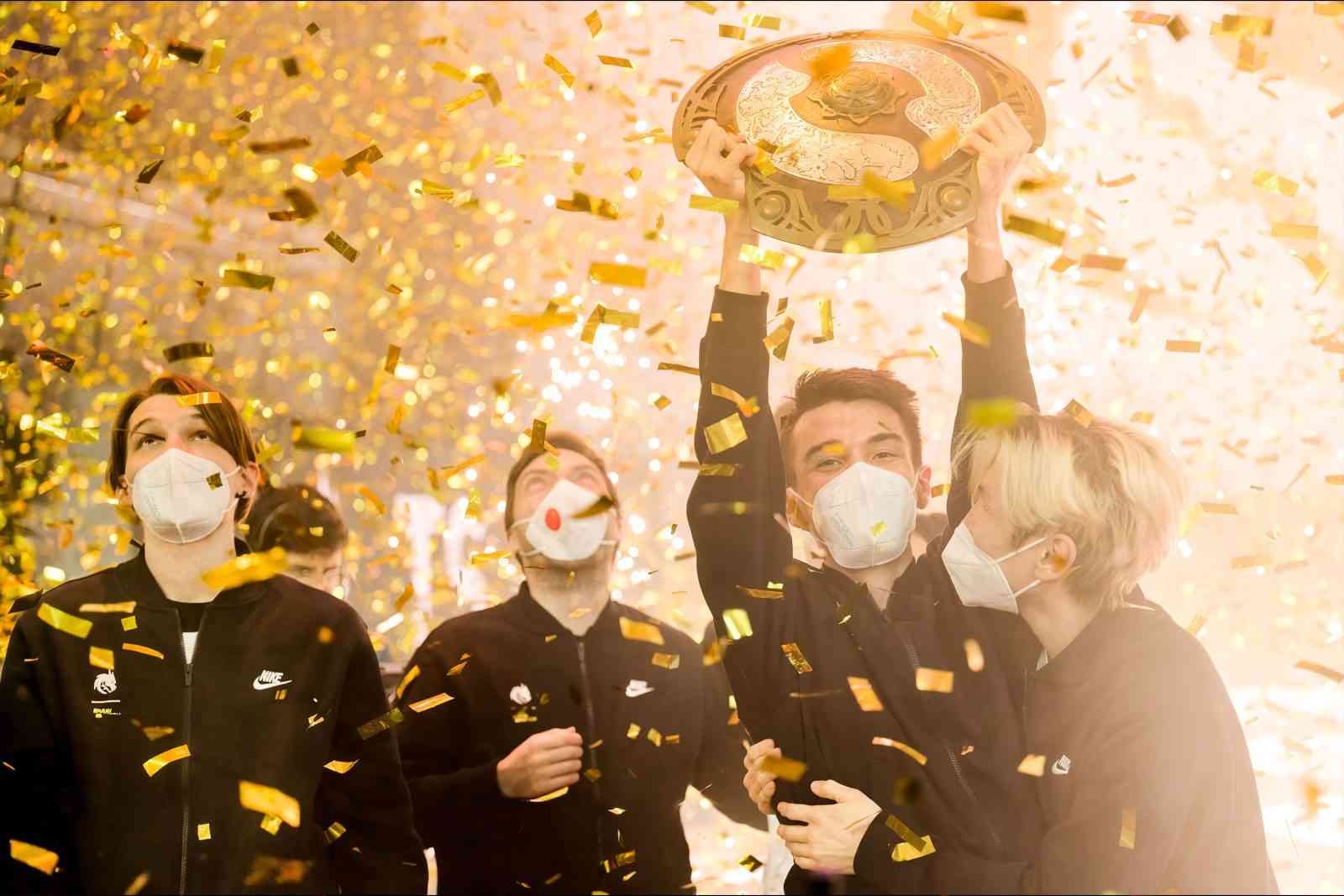 Team Spirit hold the aegis above their heads as gold ticker tape showers the stage after winning The International 10