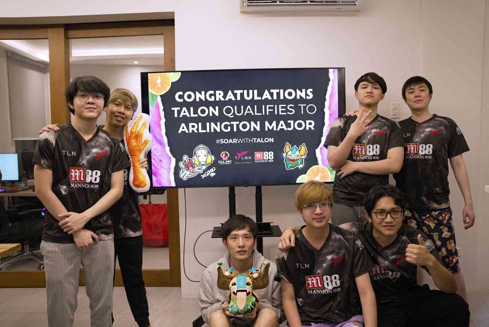 kpii and the rest of the Talon Esports roster pose around a large monitor displaying the words 