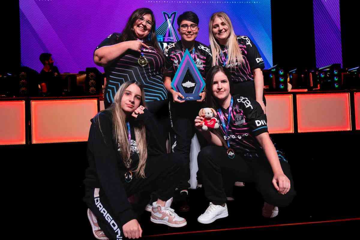 The roster for Black Dragons Female stand together on stage after a victory